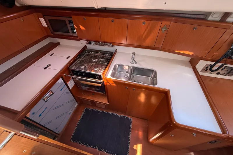 Magic Maddie 2 Yacht Photos Pics Interior of 2010 Beneteau Oceanis 43 yacht kitchen with stove, sink, and wooden cabinetry.