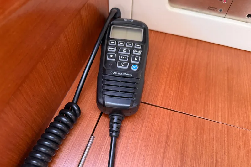 Magic Maddie 2 Yacht Photos Pics VHF radio handset on Beneteau Oceanis 43 yacht, 2010 model, resting on wooden surface.