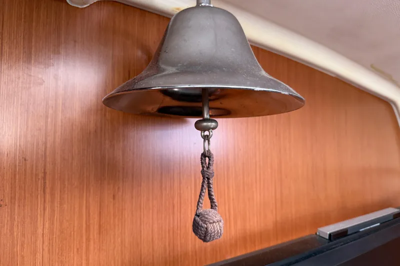 Magic Maddie 2 Yacht Photos Pics Metal bell inside 2010 Beneteau Oceanis 43 yacht, wooden interior background.