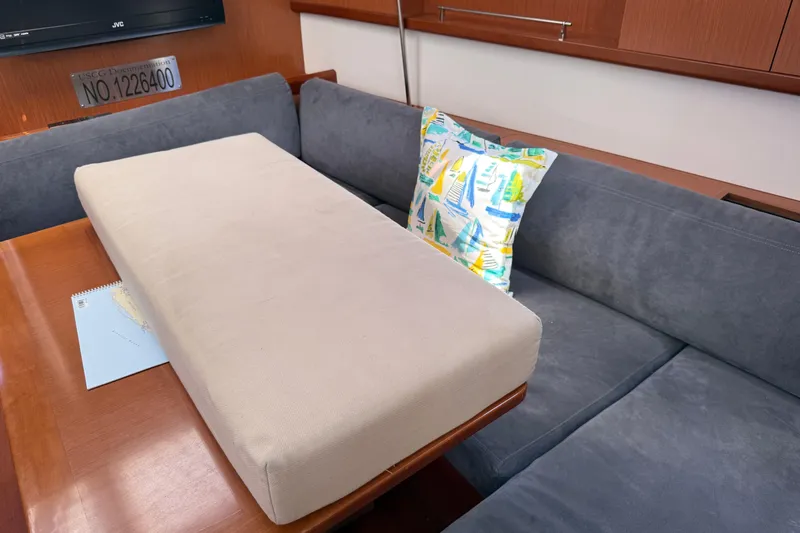 Magic Maddie 2 Yacht Photos Pics Interior of 2010 Beneteau Oceanis 43 yacht with cushioned seating and nautical-themed pillow.