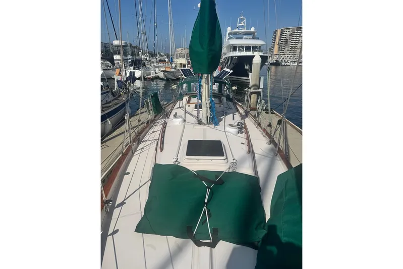 Juniper Yacht Photos Pics 1988 Pacific Seacraft 34 sailboat docked at marina, featuring green covers and clear blue sky.