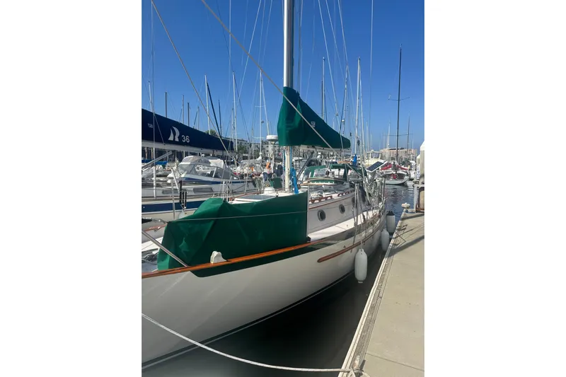Juniper Yacht Photos Pics 1988 Pacific Seacraft 34 sailboat docked at marina, featuring green covers and sleek design.