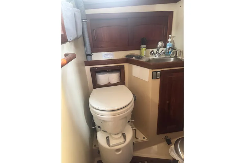 Juniper Yacht Photos Pics 1988 Pacific Seacraft 34 yacht bathroom with toilet, sink, and wooden cabinetry.