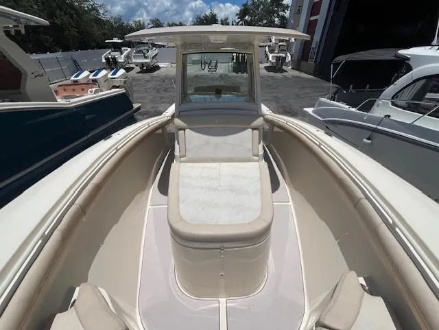  Yacht Photos Pics 2018 Scout 300LXF boat interior with seating and console, docked among other boats.