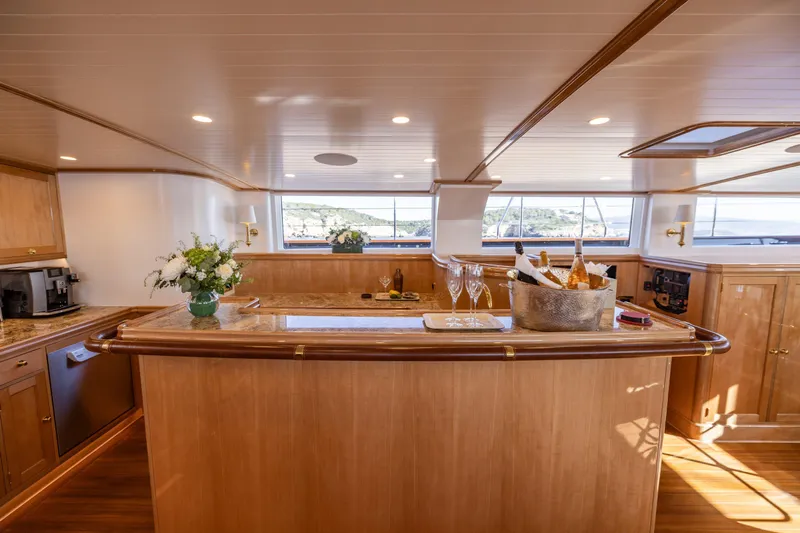 Maximus Yacht Photos Pics Luxurious interior of 2023 Vitters Cruising Ketch with elegant wooden bar and scenic windows.