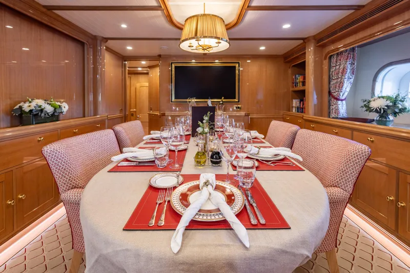 Maximus Yacht Photos Pics Luxurious dining area on 2023 Vitters Cruising Ketch yacht, elegantly set table with red accents.