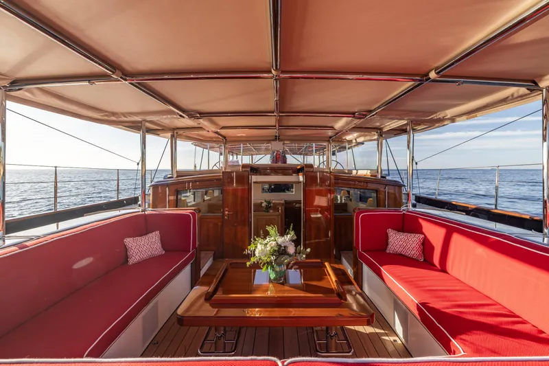 Maximus Yacht Photos Pics Luxurious 2023 Vitters Cruising Ketch interior with red seating and elegant wooden table.