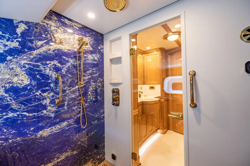 Maximus Yacht Photos Pics Luxurious bathroom in 2023 Vitters Cruising Ketch with blue marble shower and wooden cabinetry.