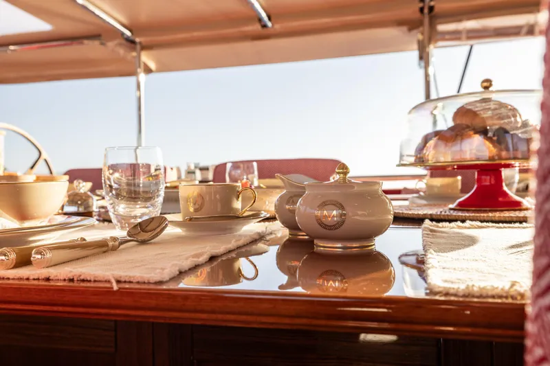 Maximus Yacht Photos Pics Luxurious dining setup on 2023 Vitters Cruising Ketch yacht, featuring elegant tableware and pastries.