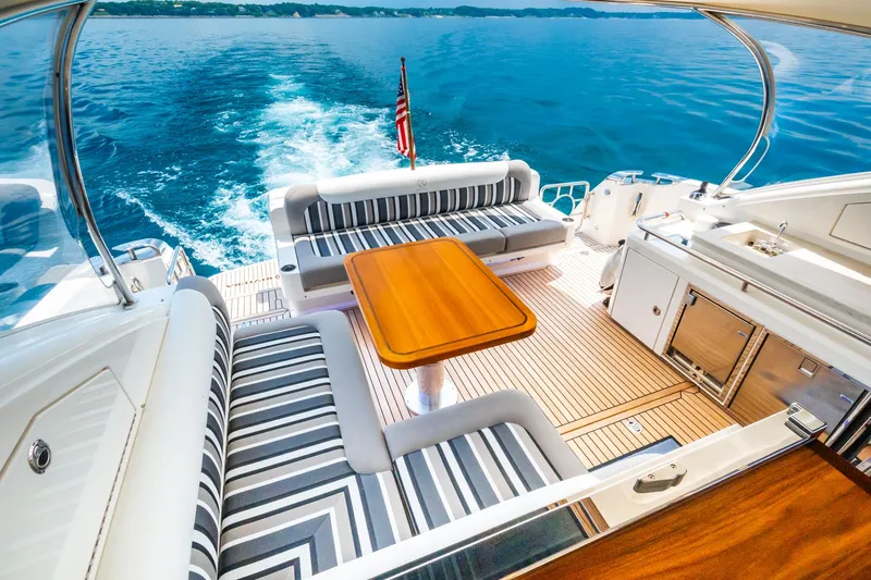 A Ro Boat Yacht Photos Pics 2019 Riviera 4800 Sport Yacht interior with striped seating, wooden table, and ocean view.