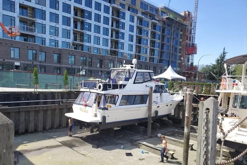 Cuatro Yacht Photos Pics 1998 Bayliner 4788 Pilot House Motoryacht in dry dock near urban construction site.