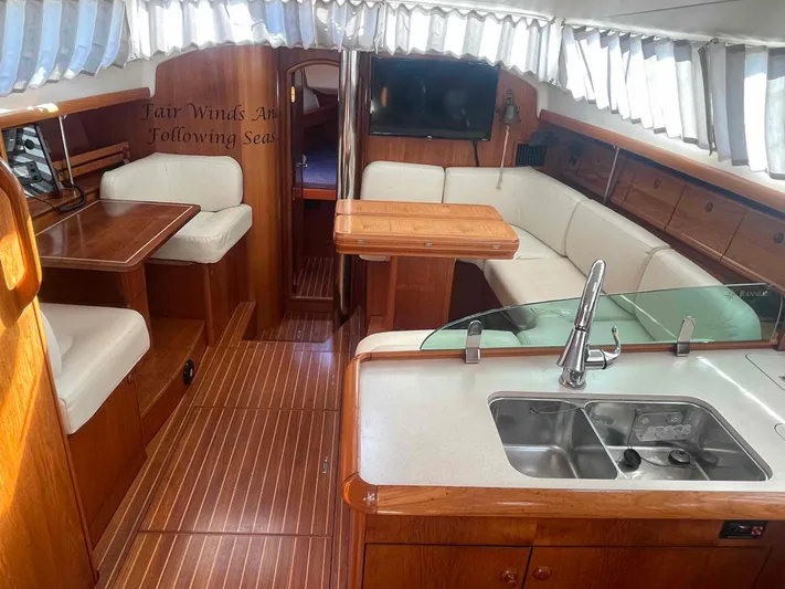 No Agenda Yacht Photos Pics 2003 Jeanneau Deck Salon interior with wood finish, white seating, and kitchen area.