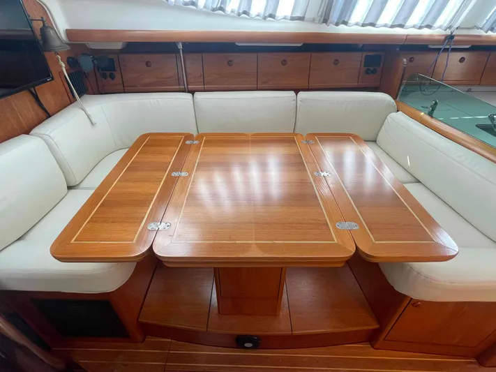 No Agenda Yacht Photos Pics 2003 Jeanneau Deck Salon interior with wooden table and white seating.