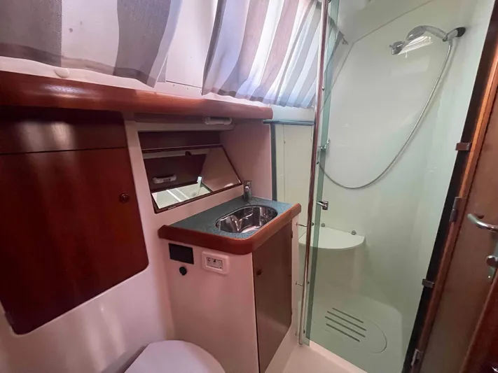 No Agenda Yacht Photos Pics 2003 Jeanneau Deck Salon bathroom with shower, sink, and wooden cabinetry.