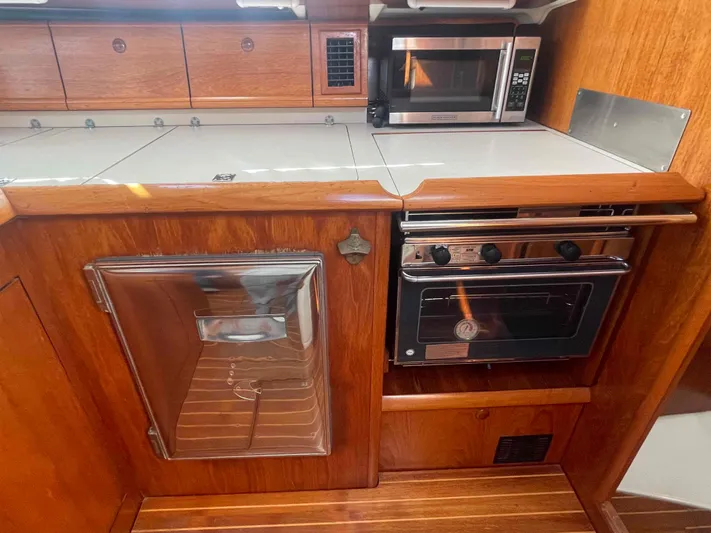No Agenda Yacht Photos Pics 2003 Jeanneau Deck Salon kitchen with wood cabinetry, oven, and microwave.