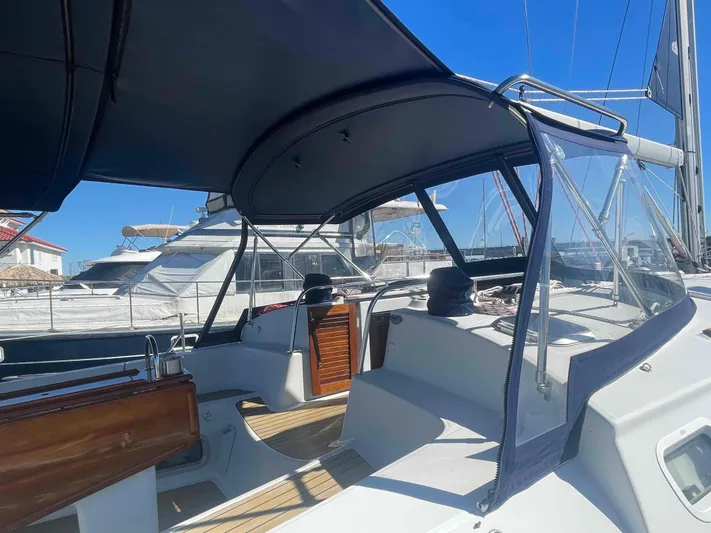 No Agenda Yacht Photos Pics 2003 Jeanneau Deck Salon sailboat with covered cockpit and wooden accents, docked in marina.