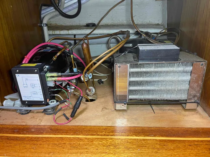 No Agenda Yacht Photos Pics Electrical components inside a 2003 Jeanneau Deck Salon boat, featuring wiring and a cooling unit.