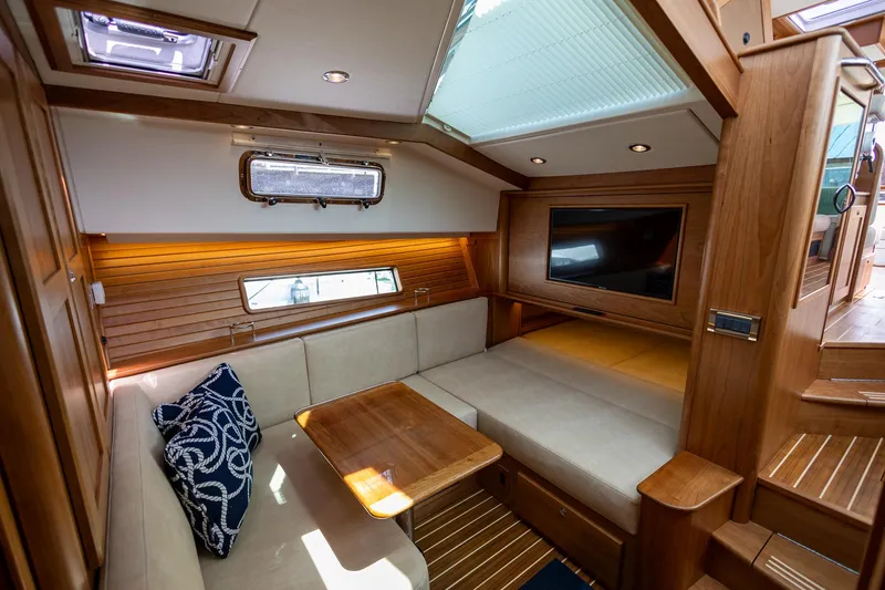 Luca Yacht Photos Pics 2023 Sabre 43 Salon Express interior with cozy seating, wooden table, and TV.