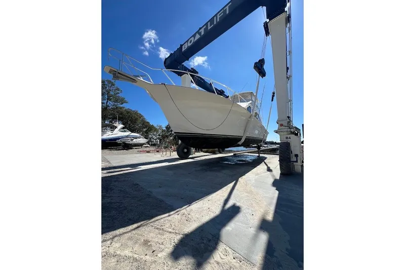 Reel Interest Yacht Photos Pics 2002 Ocean Yachts 56 Super Sport lifted by boat hoist under clear blue sky.