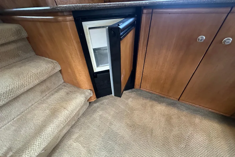 Stacey Lee Yacht Photos Pics 1999 Bayliner 4788 Pilot House Motoryacht interior with open mini fridge and carpeted stairs.