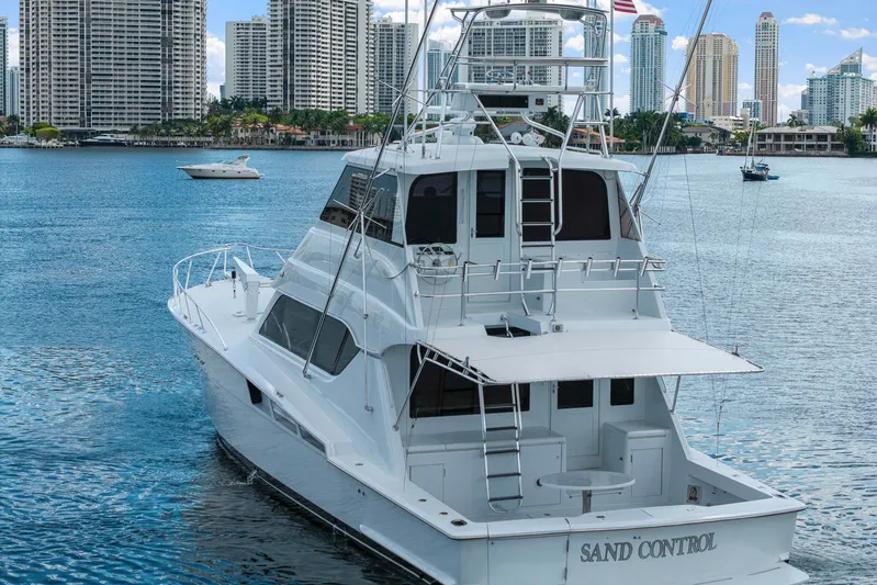 Sand Control Yacht Photos Pics 2002 Hatteras 60 Convertible yacht on water with city skyline background.