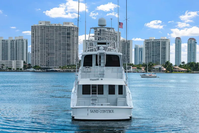 Sand Control Yacht Photos Pics 2002 Hatteras 60 Convertible yacht on water, city skyline in background.