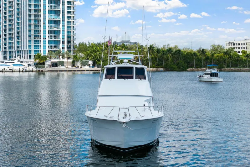 Sand Control Yacht Photos Pics 2002 Hatteras 60 Convertible yacht on calm water near modern buildings.