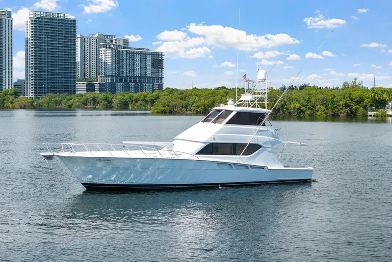Sand Control Yacht Photos Pics 2002 Hatteras 60 Convertible yacht on water with city skyline background.