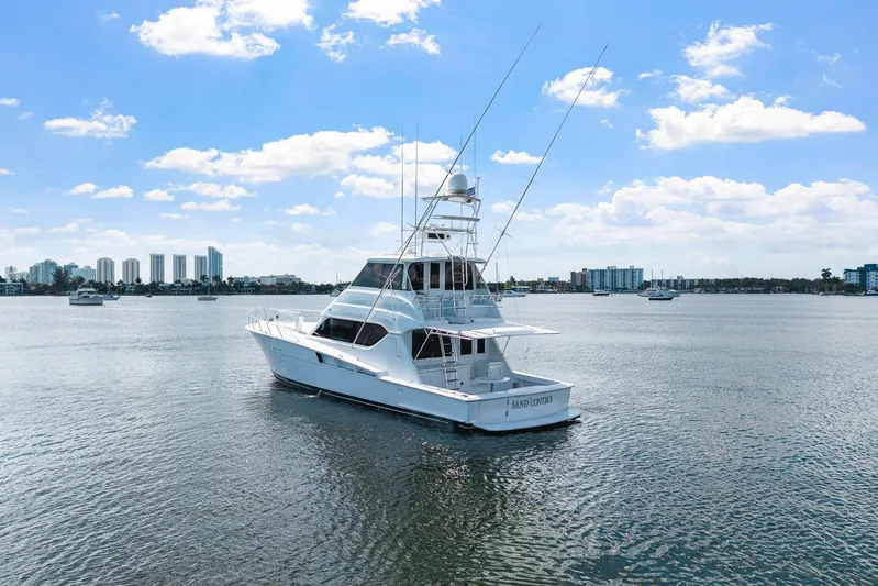 Sand Control Yacht Photos Pics 2002 Hatteras 60 Convertible yacht on calm water with city skyline background.