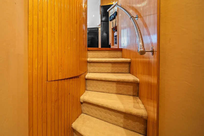 Sand Control Yacht Photos Pics Interior staircase of 2002 Hatteras 60 Convertible yacht with wooden paneling and carpeted steps.