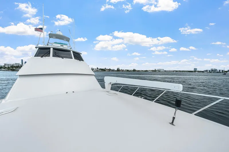 Sand Control Yacht Photos Pics 2002 Hatteras 60 Convertible yacht cruising on a sunny day with city skyline in background.