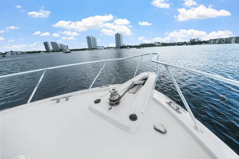 Sand Control Yacht Photos Pics Bow view of 2002 Hatteras 60 Convertible yacht on a sunny day, city skyline in background.