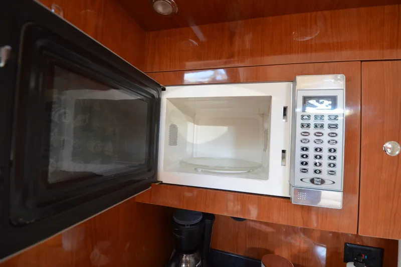  Yacht Photos Pics Open microwave in 2006 Regal Commodore 3560 yacht kitchen with wood cabinetry.
