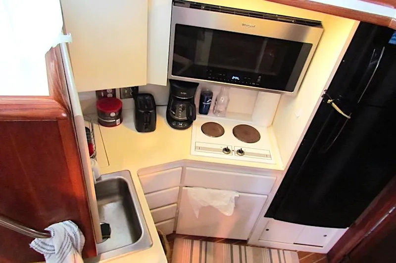  Yacht Photos Pics Compact kitchen in 1992 Hatteras 40 Motor Yacht with stove, microwave, and sink.