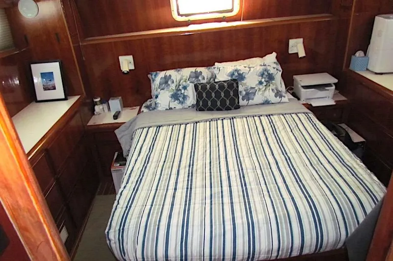 Yacht Photos Pics Cozy bedroom interior of 1992 Hatteras 40 Motor Yacht with striped bedding and wooden cabinetry.
