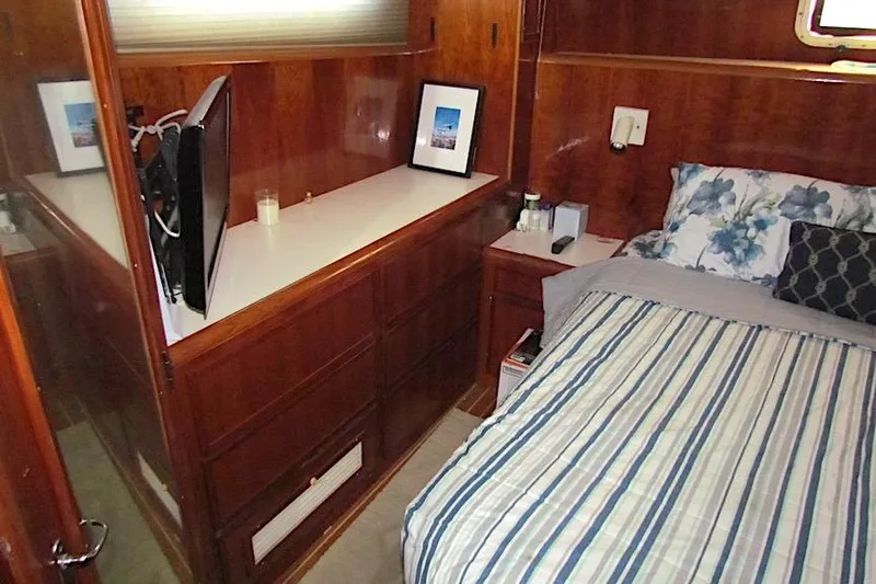  Yacht Photos Pics Cozy bedroom in 1992 Hatteras 40 Motor Yacht with wood paneling and striped bedding.