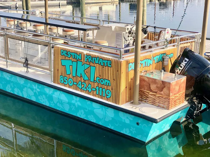 Big Kahuna Yacht Photos Pics 2022 Beachcat COI Tiki Boat docked, featuring vibrant tropical design and contact details for private charters.