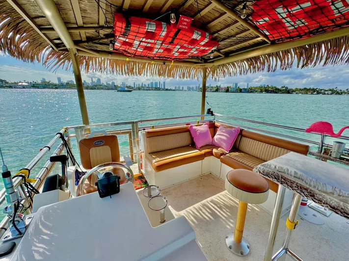 Big Kahuna Yacht Photos Pics Tiki boat interior with seating, tropical decor, and waterfront view; Beachcat COI Tiki Boat 2022.
