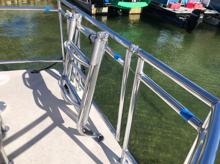 Big Kahuna Yacht Photos Pics 2022 Beachcat COI Tiki Boat with stainless steel railing on calm water.