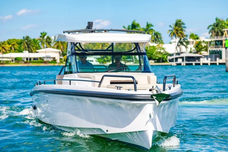 First Byte Yacht Photos Pics 2023 Axopar 37 Sun Top cruising on a sunny day with palm trees in the background.