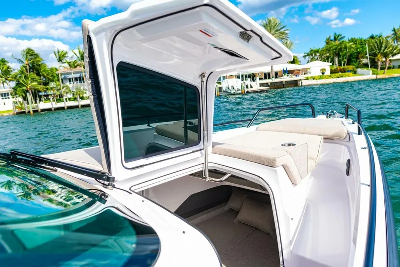 First Byte Yacht Photos Pics 2023 Axopar 37 Sun Top boat with open cabin, docked by tropical waterfront.