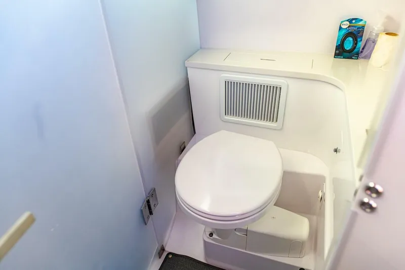 First Byte Yacht Photos Pics Compact bathroom in 2023 Axopar 37 Sun Top boat, featuring a modern toilet and storage.