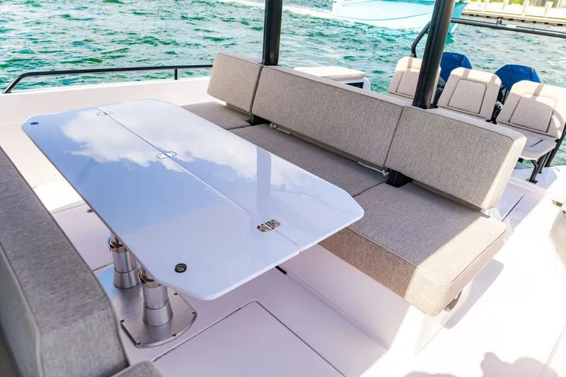 First Byte Yacht Photos Pics 2023 Axopar 37 Sun Top boat interior with sleek seating and table by the water.