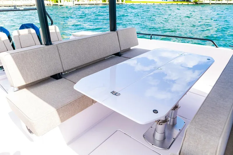 First Byte Yacht Photos Pics 2023 Axopar 37 Sun Top boat interior with cushioned seating and sleek table design.
