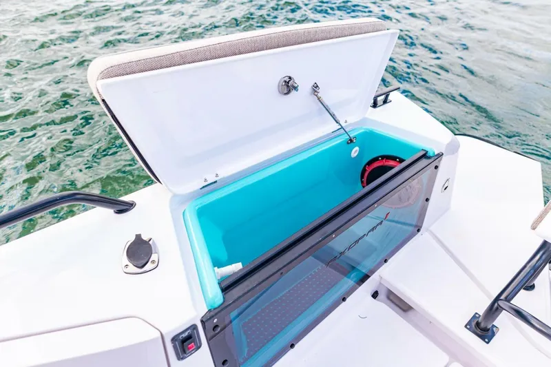 First Byte Yacht Photos Pics Open storage compartment on 2023 Axopar 37 Sun Top boat, with blue interior and water backdrop.