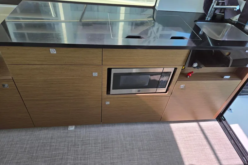  Yacht Photos Pics Modern kitchen area in a 2020 Jeanneau NC 1095 boat with microwave and sink.