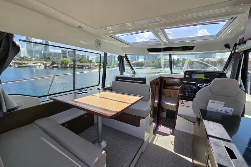  Yacht Photos Pics Interior of 2020 Jeanneau NC 1095 boat with dining area and helm, overlooking waterfront.