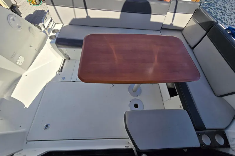  Yacht Photos Pics 2020 Jeanneau NC 1095 boat cockpit with wooden table and cushioned seating.