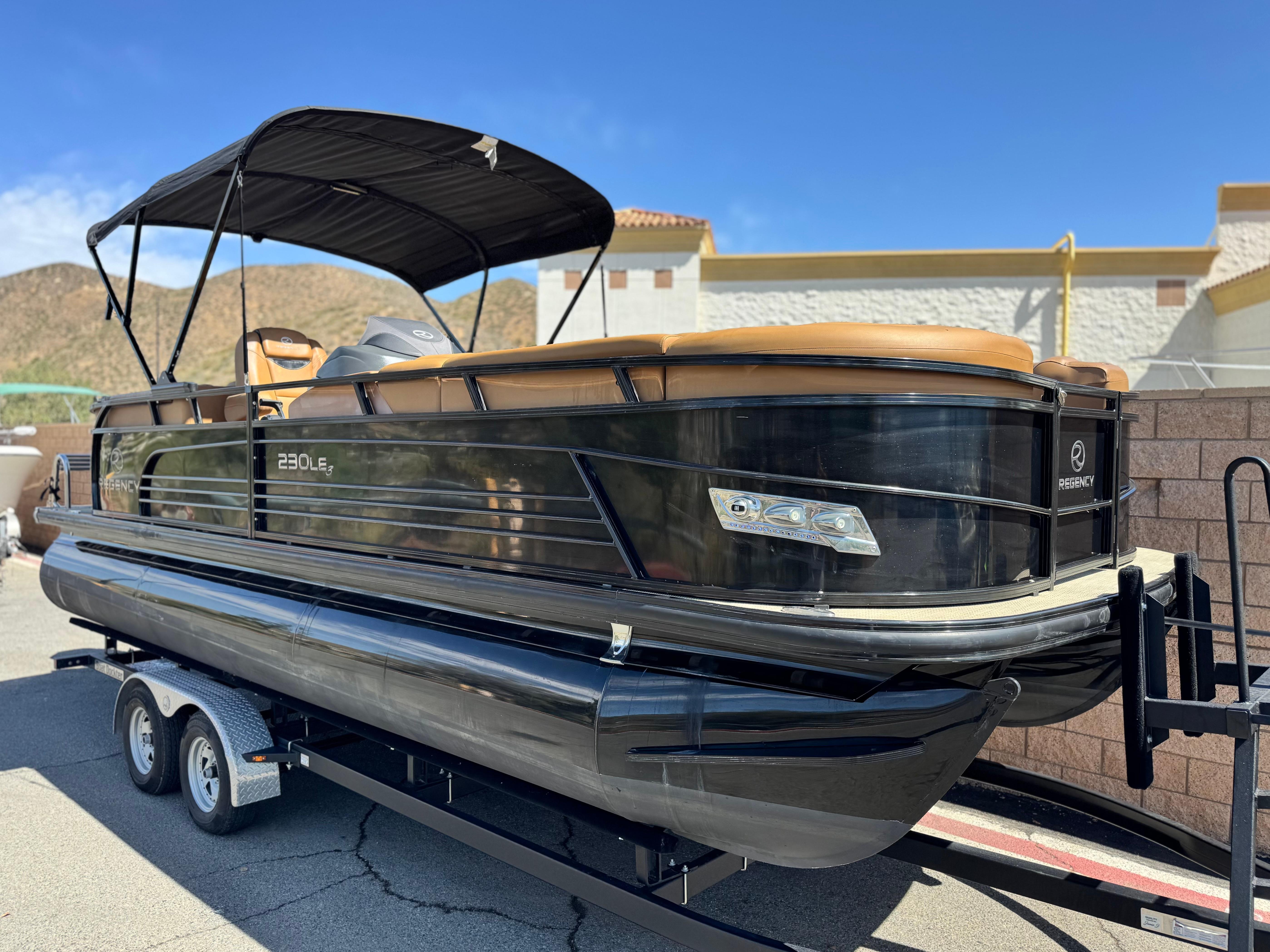 2021 Regency 230 LE3 pontoon boat on trailer, featuring sleek black design and canopy.