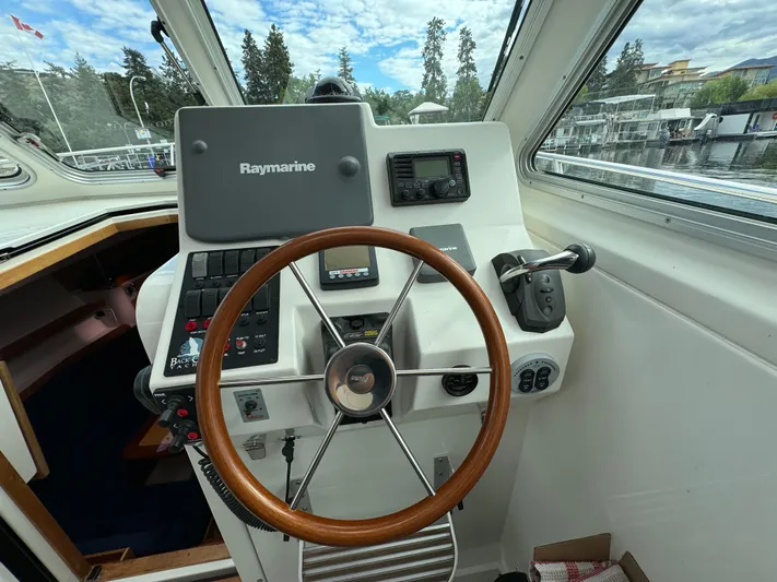 "flying Low" Yacht Photos Pics Helm of 2008 Back Cove 33 boat with Raymarine navigation system and wooden steering wheel.